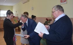 dwie, trzy osoby wręczają innej dyplom i kwiaty