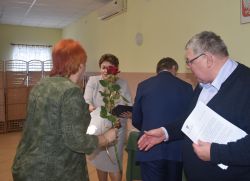 dwie, trzy osoby wręczają innej dyplom i kwiaty