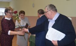 dwie, trzy osoby wręczają innej dyplom i kwiaty