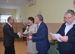 dwie, trzy osoby wręczają innej dyplom i kwiaty