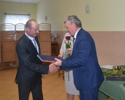 dwie, trzy osoby wręczają innej dyplom i kwiaty
