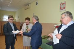 dwie, trzy osoby wręczają innej dyplom i kwiaty