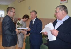 dwie, trzy osoby wręczają innej dyplom i kwiaty