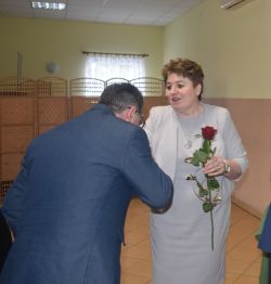 dwie, trzy osoby wręczają innej dyplom i kwiaty