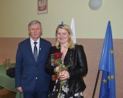 dwie, trzy osoby wręczają innej dyplom i kwiaty