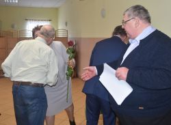 dwie, trzy osoby wręczają innej dyplom i kwiaty