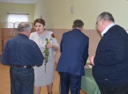 dwie, trzy osoby wręczają innej dyplom i kwiaty