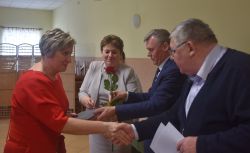dwie, trzy osoby wręczają innej dyplom i kwiaty