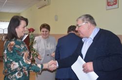 dwie, trzy osoby wręczają innej dyplom i kwiaty