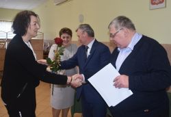 dwie, trzy osoby wręczają innej dyplom i kwiaty