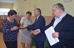 dwie, trzy osoby wręczają innej dyplom i kwiaty