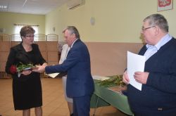 dwie, trzy osoby wręczają innej dyplom i kwiaty