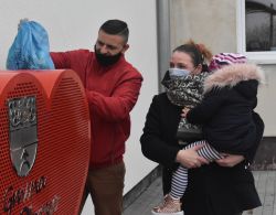 czworo ludzi stojących przy pojemniku w kształcie serca na nakrętki od butelek