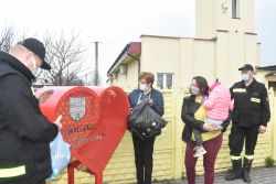 Ludzie zgromadzeni wokół stalowego pojemnika w kształcie serca