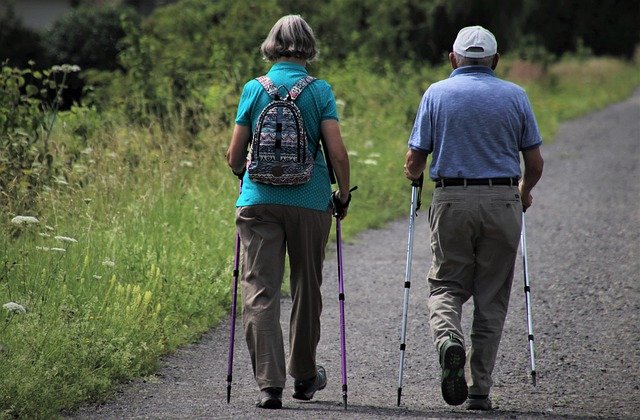 dwoje starszych ludzi maszeruje z kijkami nordic walking